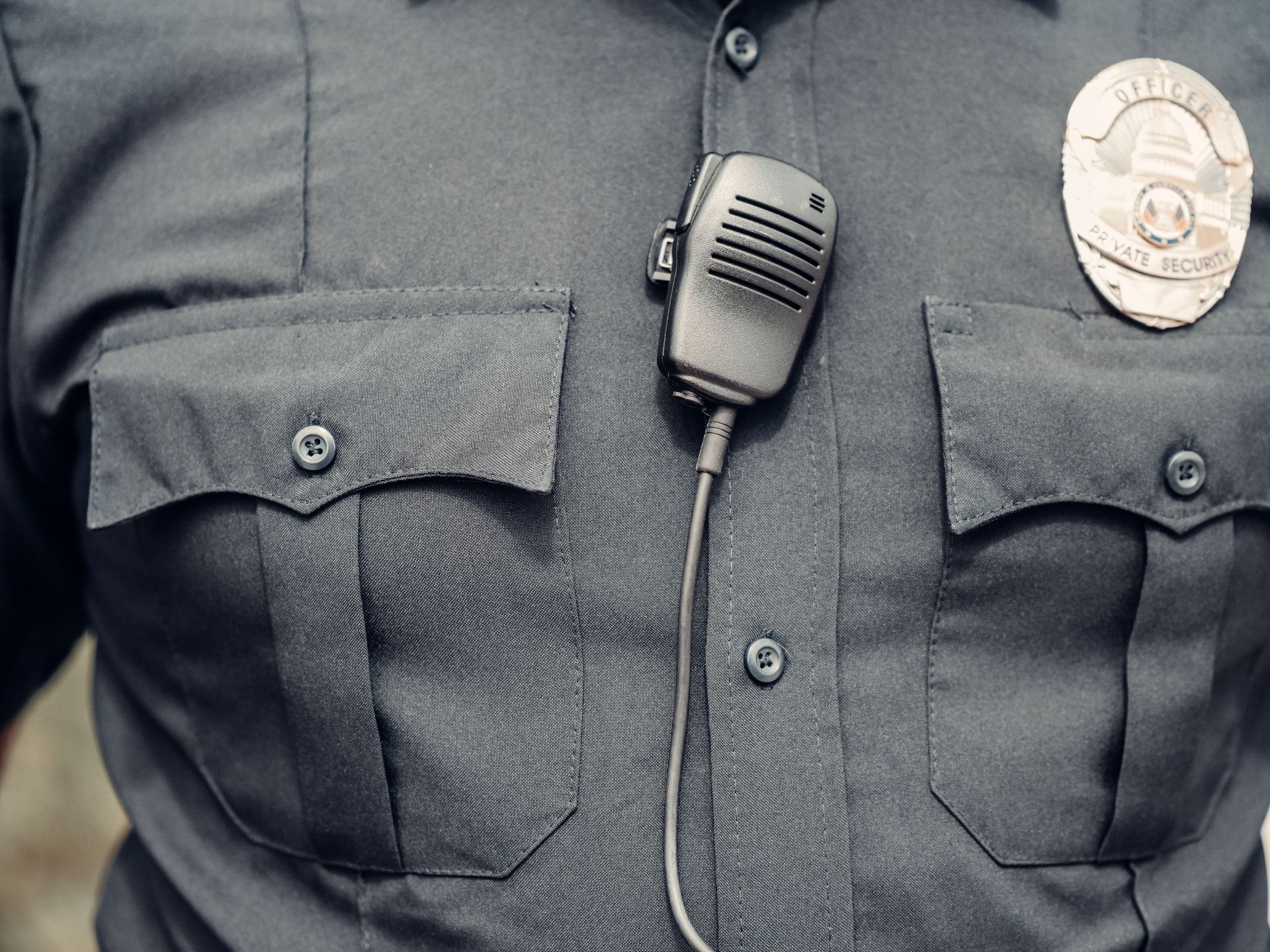 Close-up of a police officer's uniform featuring a body camera and badge.