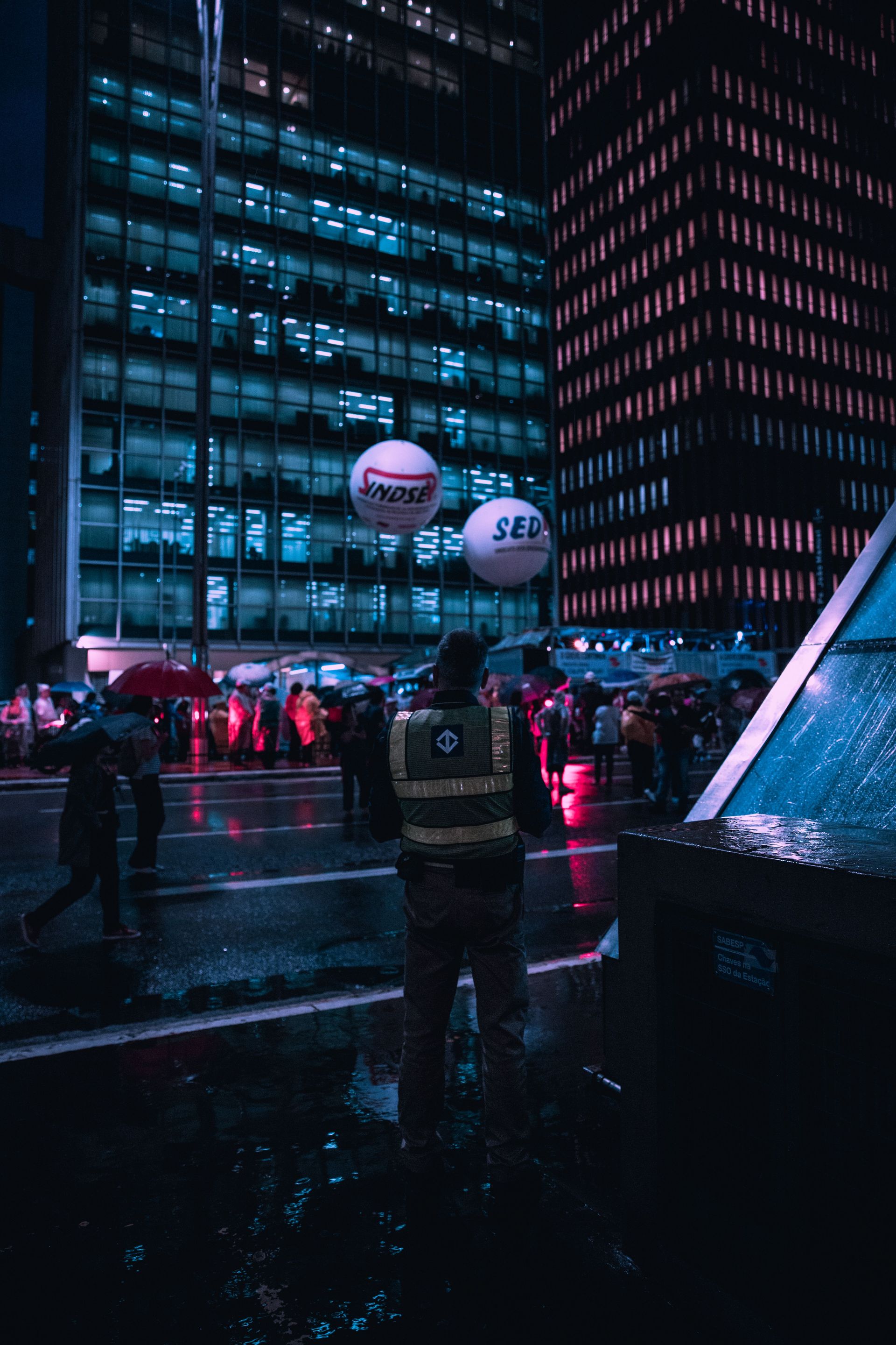 Nighttime view of a bustling urban street with people and colorful lights.