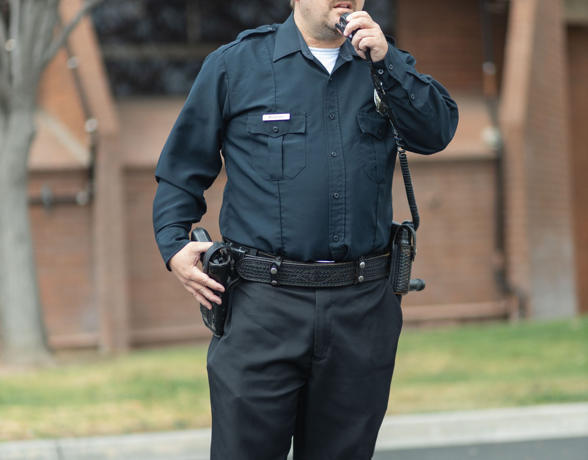 A police officer in uniform communicates via radio, exuding public safety authority.